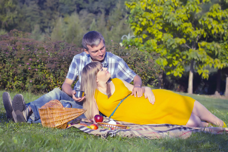 怀孕对年轻情侣在公园里野餐放松