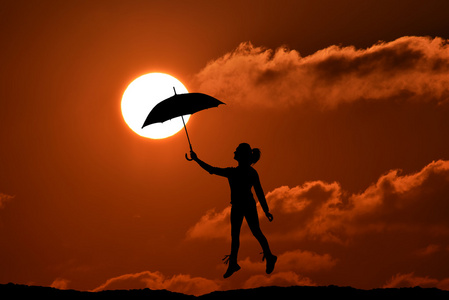 伞的女人跳和日落与大太阳，景观的剪影