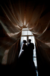 剪影的新娘和新郎在窗口的背景上无线