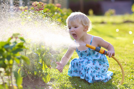 可爱的小女孩在花园里的花浇水图片