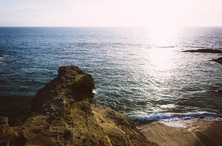 峭壁和表岩石海滩，在太平洋上空夕阳中