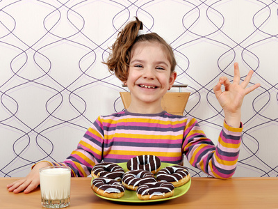 快乐的小女孩，与巧克力甜甜圈和 ok 手势