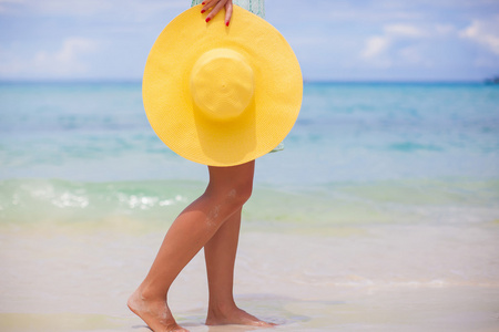 黄色的帽子，在海滩上的女性手的特写