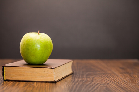 苹果和木制的桌子上的书