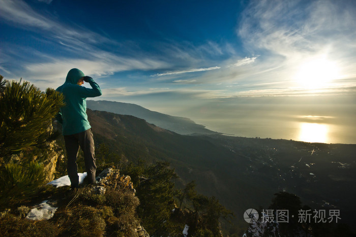 男人站在山的峭壁上在日出