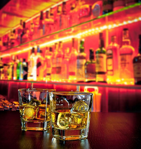 在温暖的气氛下，在威士忌瓶附近的吧台上放几杯加冰块的威士忌