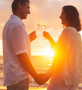 日落时分，一对情侣在海滩上喝香槟