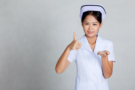亚洲年轻护士手掌上拿着药片竖起大拇指