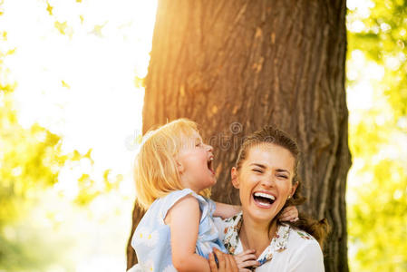 快乐的妈妈和小女孩站在树旁