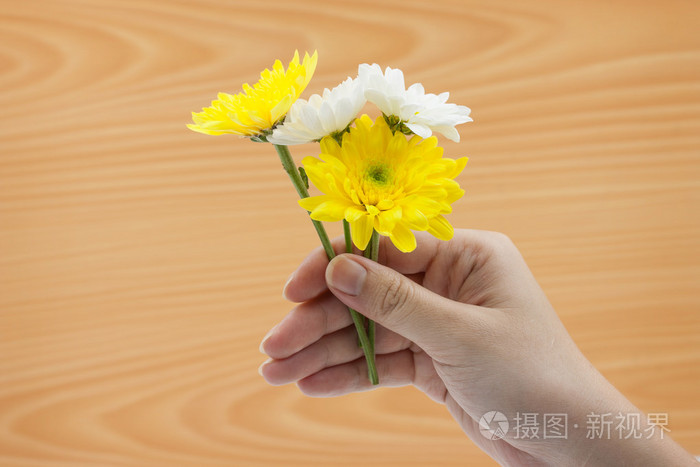 女人手拿着一束鲜花木制背景