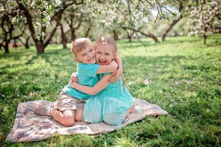 快乐的弟弟和妹妹在春天苹果盛开的花园里玩