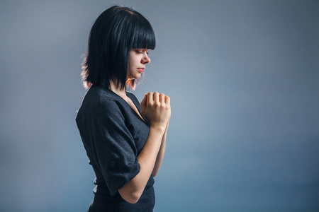 欧洲外观黑发女孩紧握她的手在祷告上