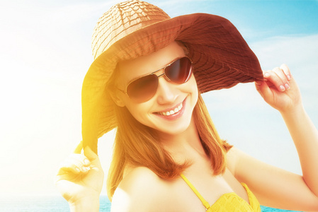 墨镜和一顶帽子在海滩上的年轻快乐的女人