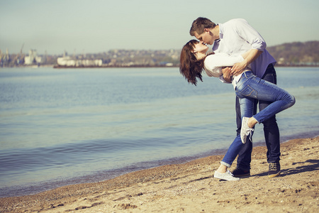 开朗的夫妇拥抱合影在沙滩上阳光明媚的日子。图片 照片 的对幸福的夫妻，在海滩上玩。时髦的样式。室外拍摄