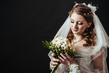 时装模特与黑色演播室背景在喝香槟，身穿婚纱的新娘花束