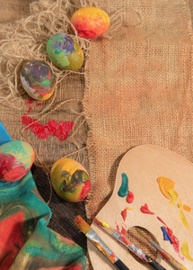 复活节彩蛋与画家的画笔 木制调色板和手绘布，安排在画布上