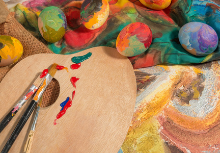 复活节彩蛋与两个画家的画笔，一个木制的调色板和手绘布