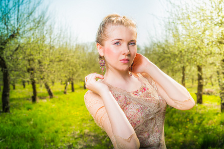 站在花园里的苹果树附近的美丽年轻的金发女郎