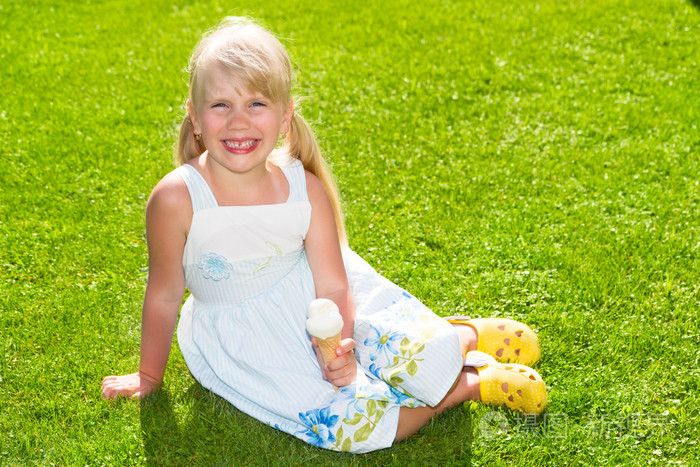 冰淇淋在草地上的可爱微笑的小女孩