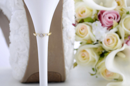 在美丽的白色高跟鞋鞋后跟上的结婚戒指