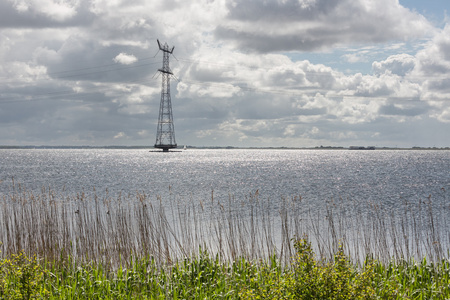 电力塔在荷兰湖与许多的太阳反射