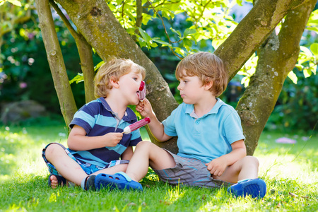 两个小的同级男孩在家里吃红色的冰激淋的花园