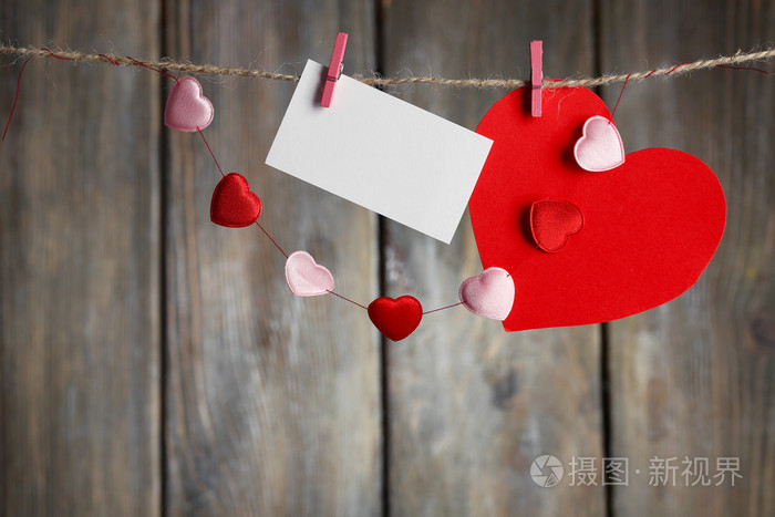 明亮的心和卡挂在绳子上木制背景