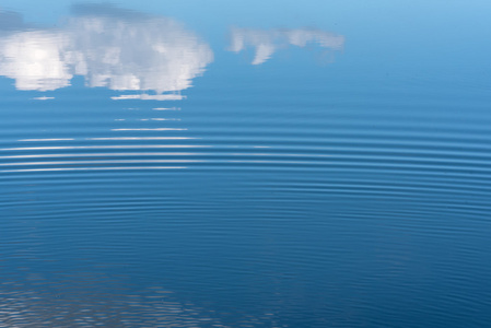 抽象的湖水的自然背景，天空的倒影，水上的云彩和美丽的小波浪