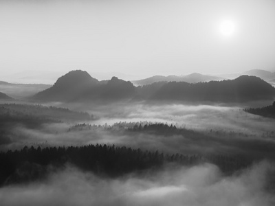 美丽的山内反演的秋天日出。从雾背景增加峰山。黑白照片