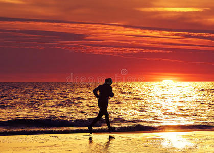 日落时，女性慢跑者在海滩上跑步。