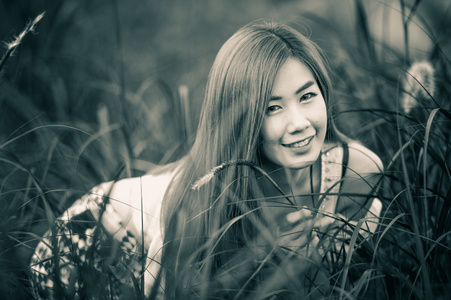 肖像泰国漂亮的女孩坐在草地上
