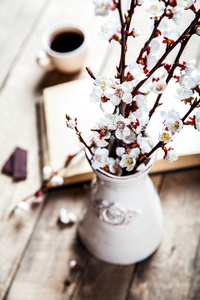 打开的古董书，樱桃树开花支上的木桌和一个美丽的古董花瓶