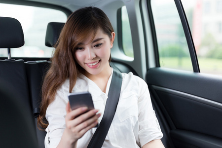 在汽车中使用移动电话的亚洲女人