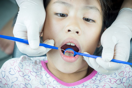 小女孩带着牙医检查病人的牙齿图片