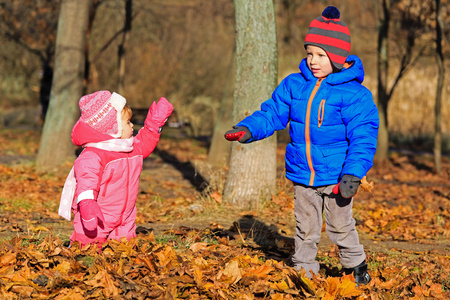 男孩和女孩玩在秋天的落叶