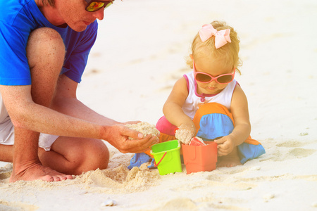 父亲和小女儿在海滩上玩沙子