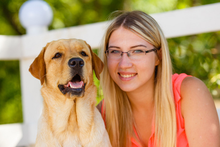 美丽的年轻女孩的肖像与她的狗拉布拉多猎犬户外在夏季美丽的公园