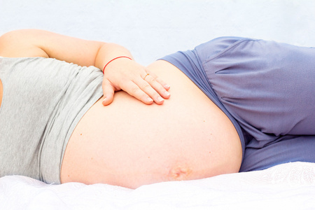 一个怀孕的女人是躺着，抚摸着她的肚子