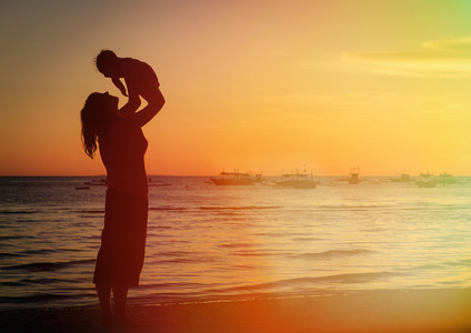 母亲和女儿在日落海滩玩