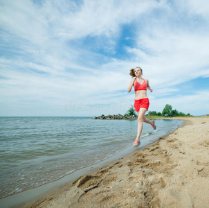 在阳光明媚的夏日沙滩上奔跑的年轻女士。训练。慢跑
