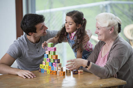 一个女孩在家里的桌子上玩着爸爸和奶奶的字母积木