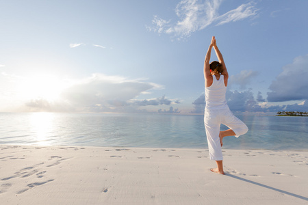 练瑜伽在海滨的白种女人