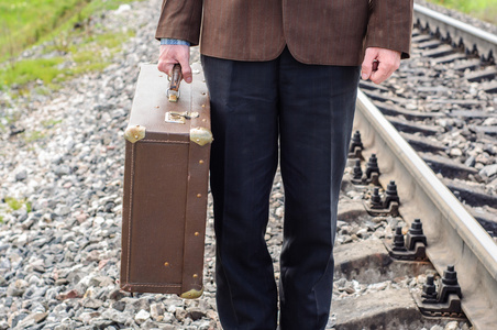与旧复古手提箱在铁路上的人时髦