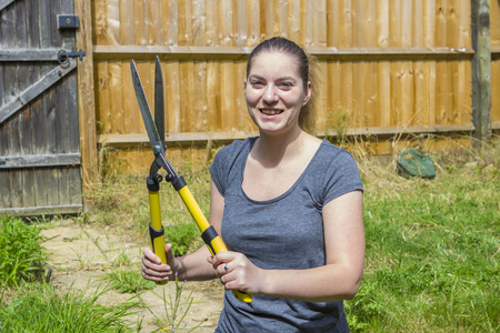 年轻女子与花园剪在花园里工作