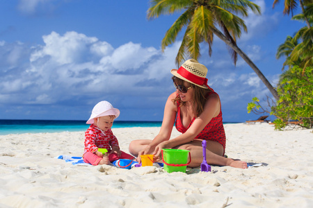 母亲和小女儿在热带海滩上玩