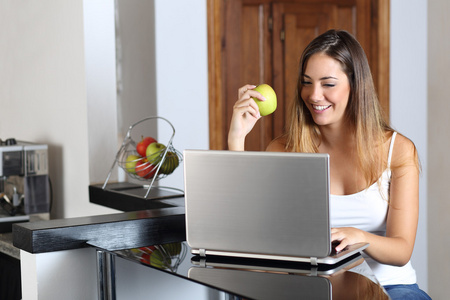浏览一台笔记本电脑和在家吃的企业家女人
