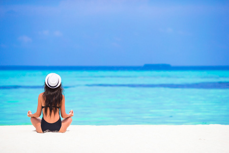 年轻女子坐在瑜伽位置在热带度假期间