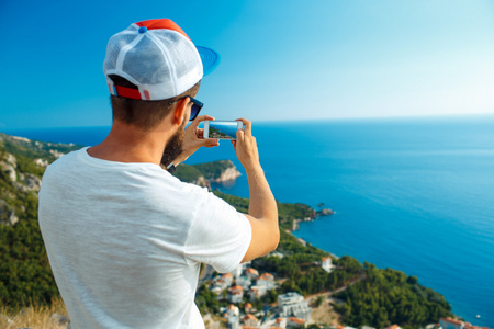男人通过智能手机背景下海洋海岸使照片