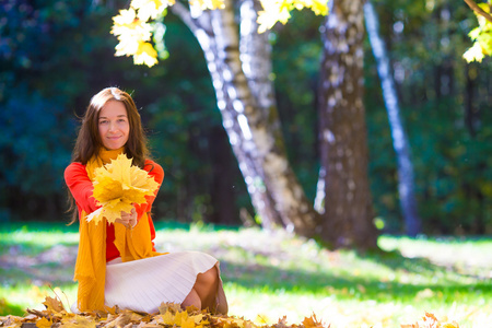 幸福的年轻女人，与黄色枫叶叶在户外在美丽的秋天公园