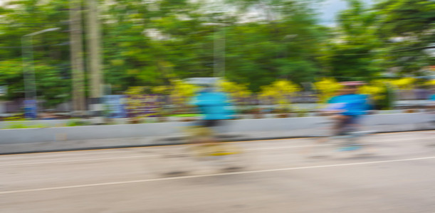 模糊骑自行车图像的赛车骑手在道路上。 用慢速快门技术拍照。
